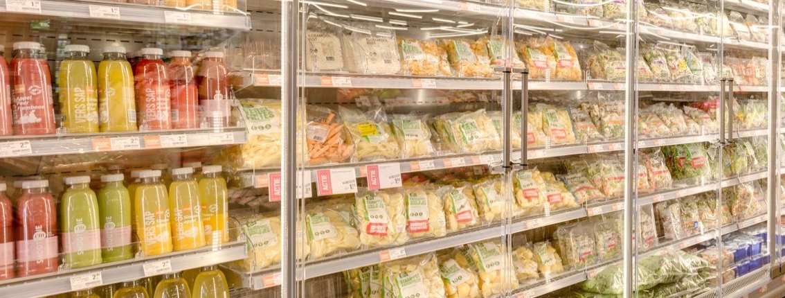 Filled refrigerated display cases with fresh juices, vegetables and salads in a supermarket